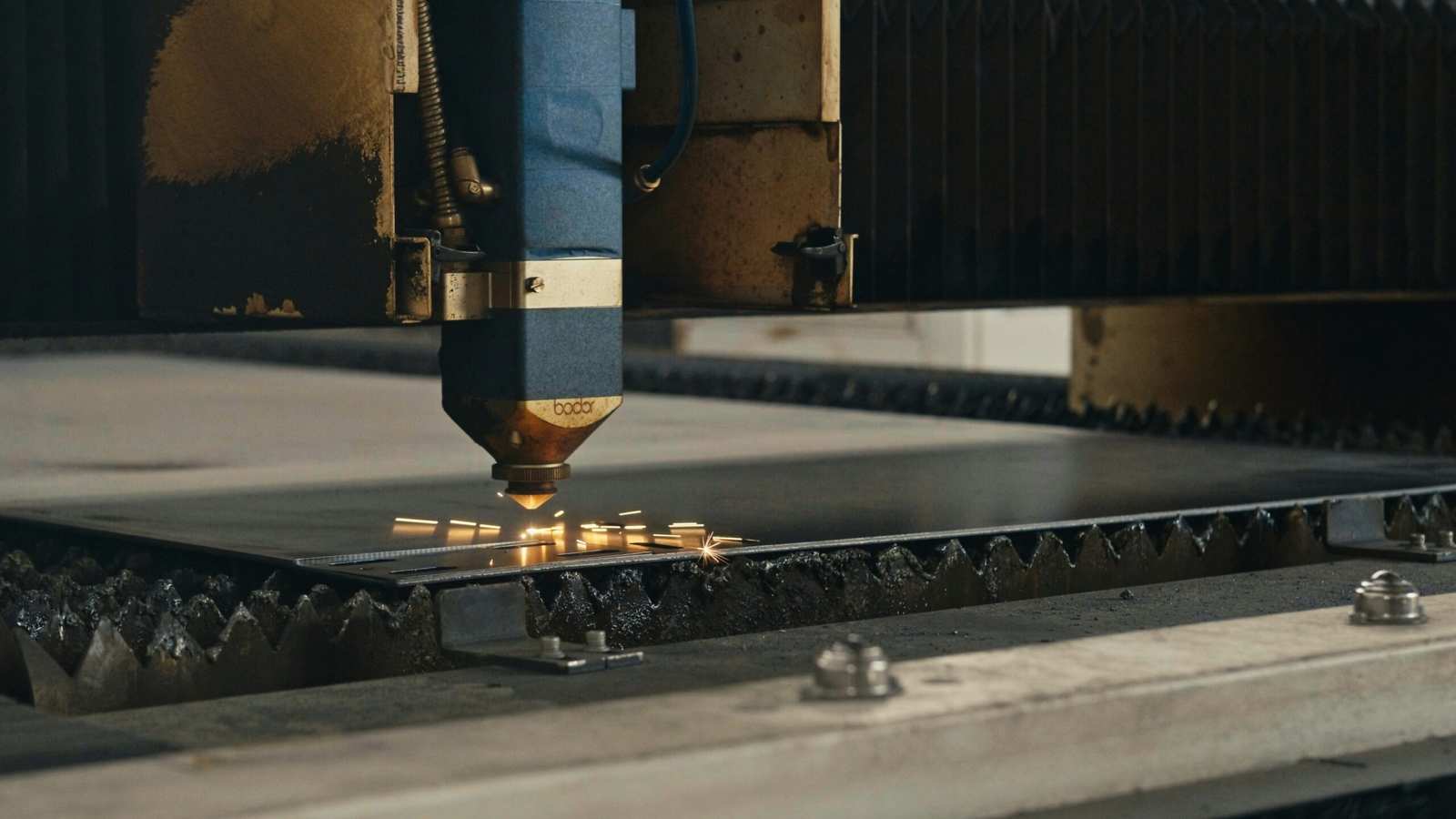 Laser cutting machine cutting through metal sheet with sparks